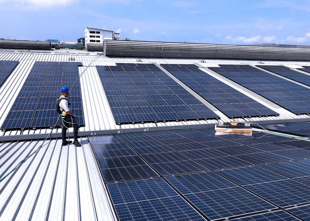 Man operating a mechanized robot cleaning solar panels with safety